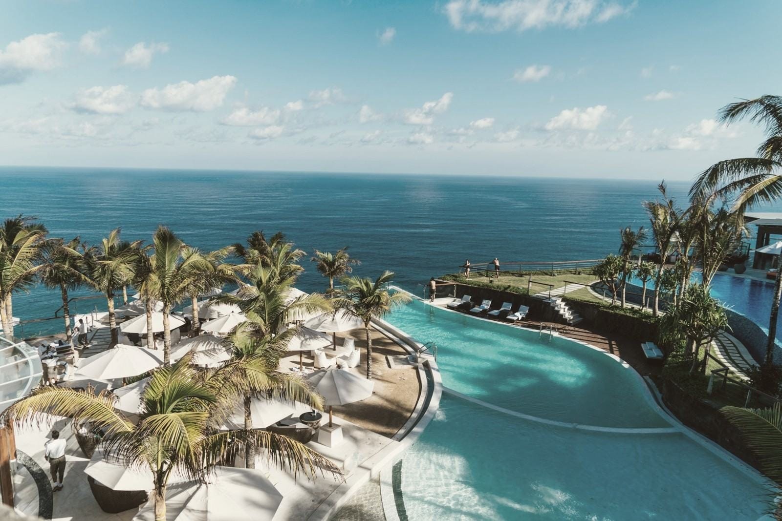 Palm trees and a pool terrace above the sea at dusk